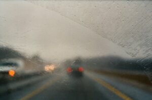 The view from a wet car windshield looking into traffic