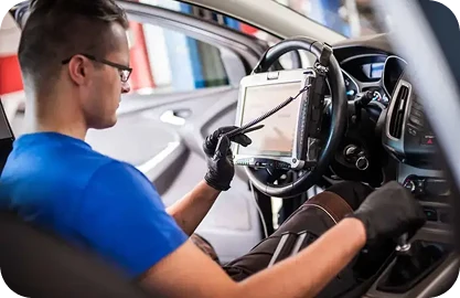 A technician performing a safety systems recalibration on a vehicle using advanced diagnostic equipment.