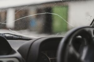 Automobile special workers remove old windscreen or windshield of a car in auto service station garage