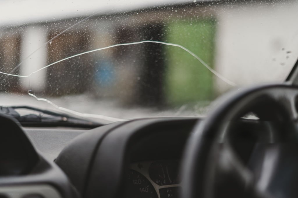 Automobile special workers remove old windscreen or windshield of a car in auto service station garage