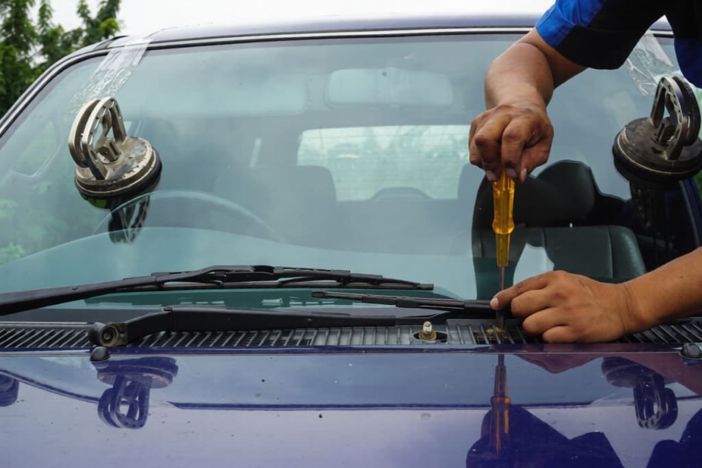Glazier using tools repairing to fix crack broken windshield on the front window glass