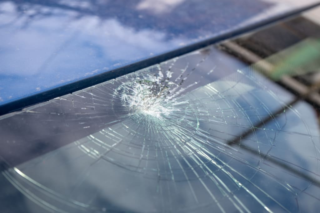 broken windshield with a lot of cracks and small glass pieces, damaged car