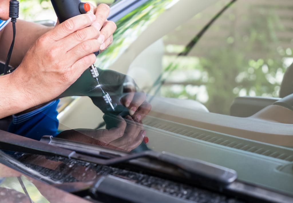 A man fixing windshield crack using tool