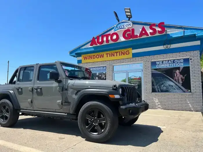 Gray Jeep Wrangler parked outside Save On Auto Glass on a sunny day.