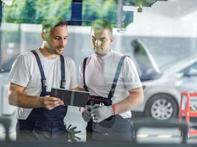 Auto mechanics cooperating while using touchpad in a workshop