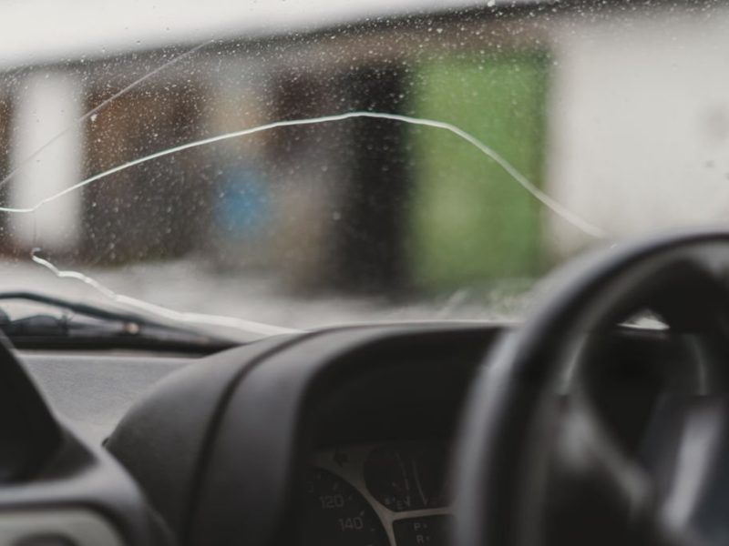 Automobile special workers remove old windscreen or windshield of a car in auto service station garage