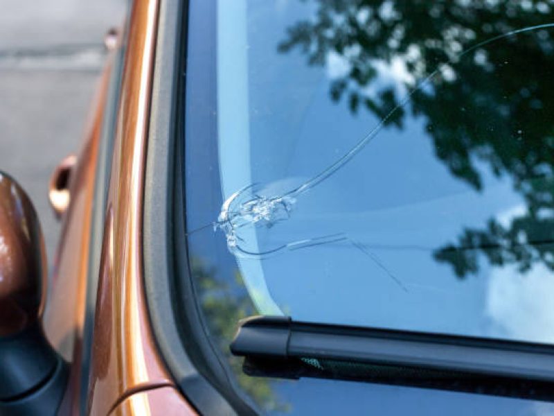 Broken car windshield glass from stone. Damaged windscreen on vehicle, close up