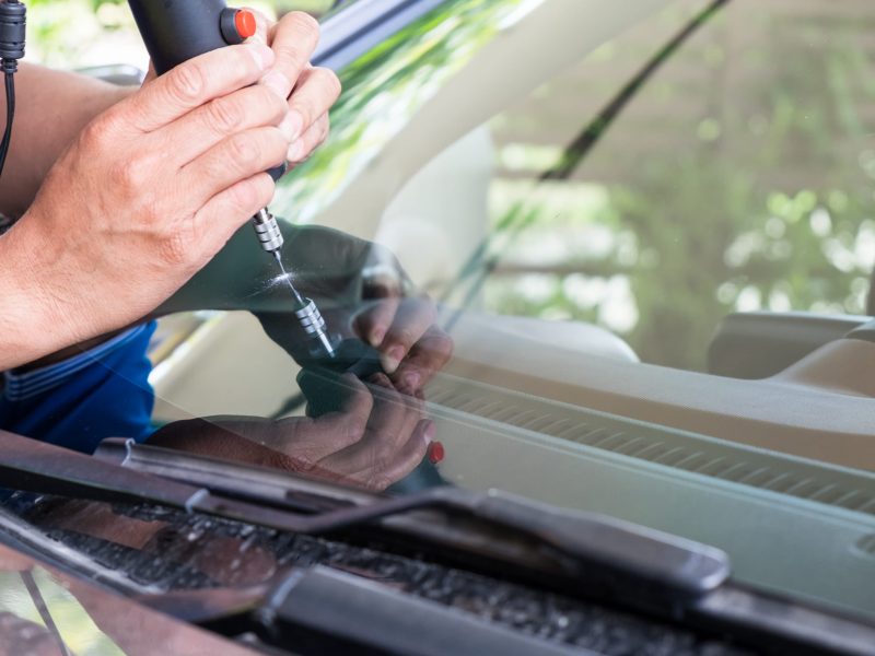 A man fixing windshield crack using tool